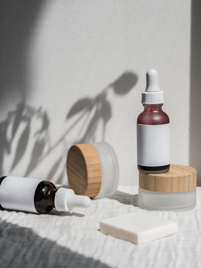 services-01 Minimalist arrangement of natural cosmetic jars and droppers with wooden lids, featuring soft shadows and bright lighting.